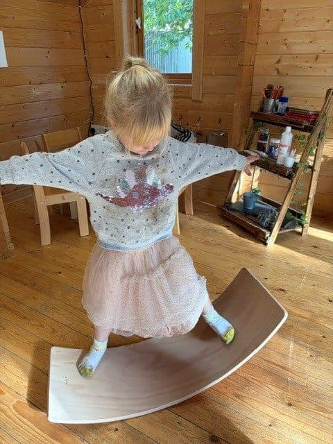 A child balancing on a wooden balance board at The Manor House Nursery in Bristol