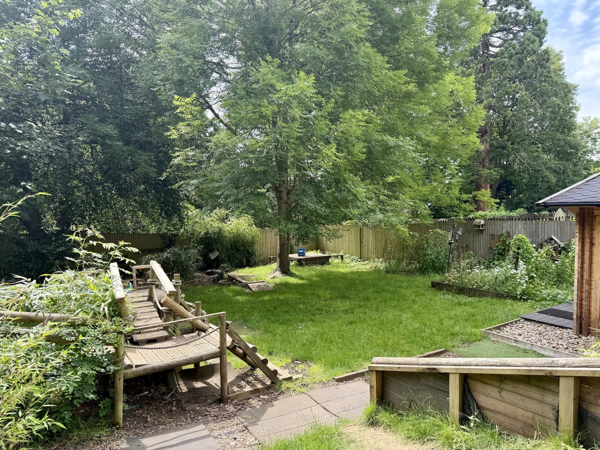 Trees, lawn and a wooden climbing trail in the garden at The Manor House Nursery, Westbury on Trym