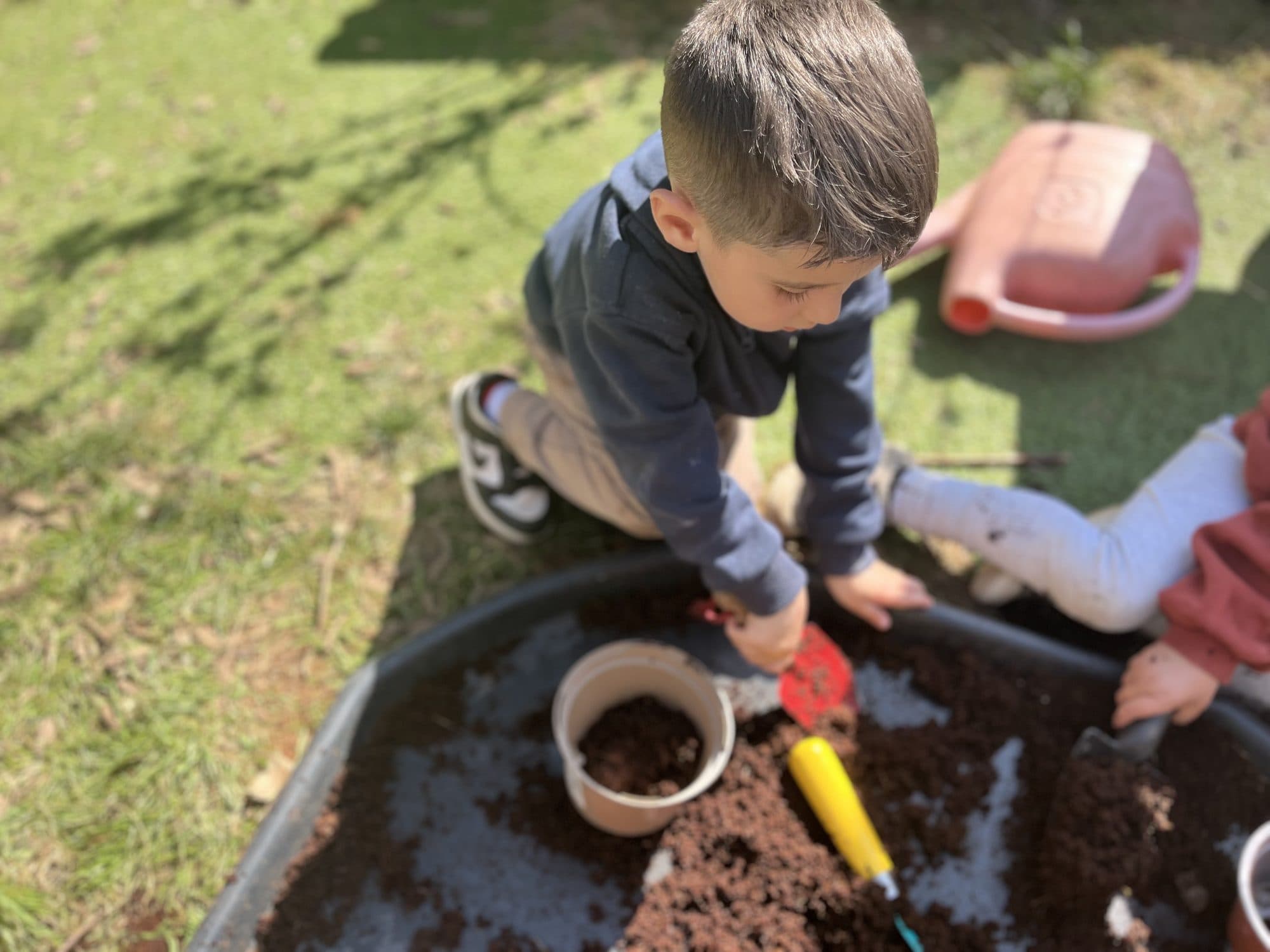 Children digging in a mud tray in the garden at The Manor House Nursery, Bristol