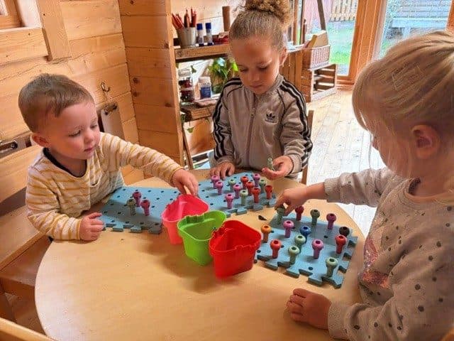 Toddlers building with peg boards at The Manor House Nursery in Bristol