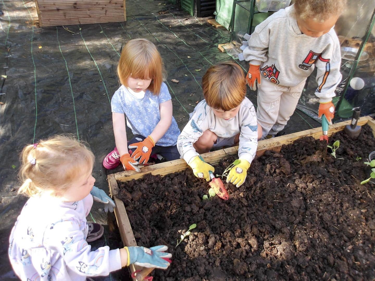 Toddlers planting in a raised bed at The Manor House Nursery in Bristol