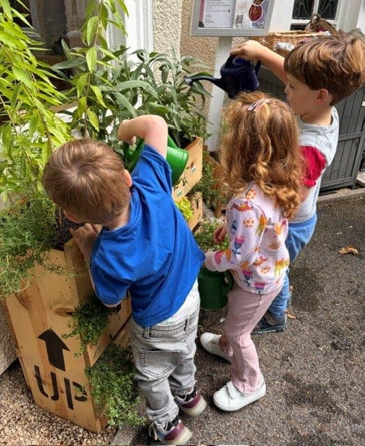 Children watering plants in the garden at The Manor House Nursery, Westbury on Trym