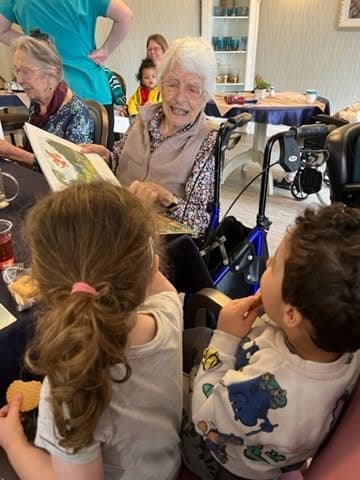 Children from The Manor House Nursery sharing a story with a resident at Trymview Hall, Westbury on Trym